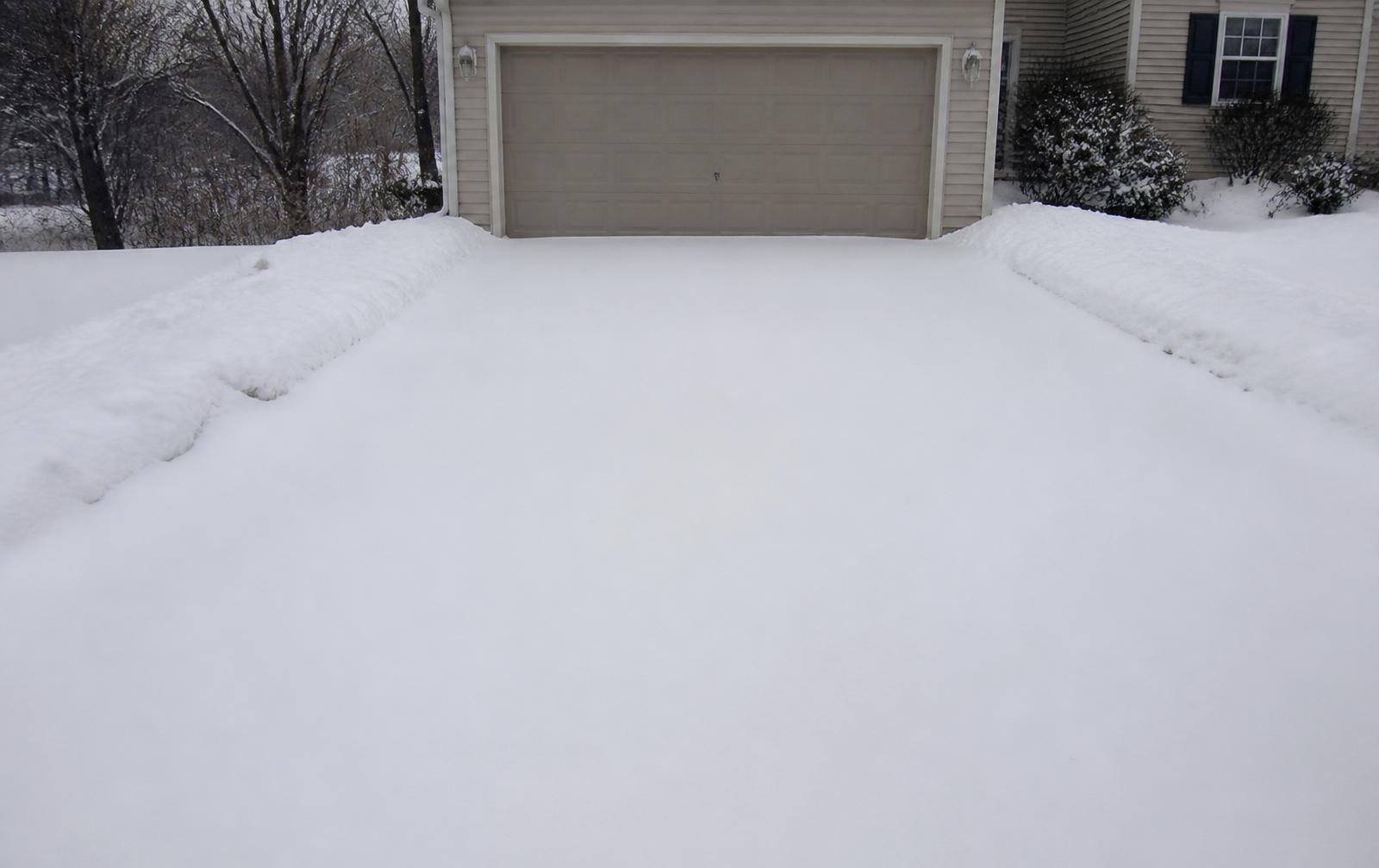 Untouched snow across an empty residential driveway on an overcast winter morning